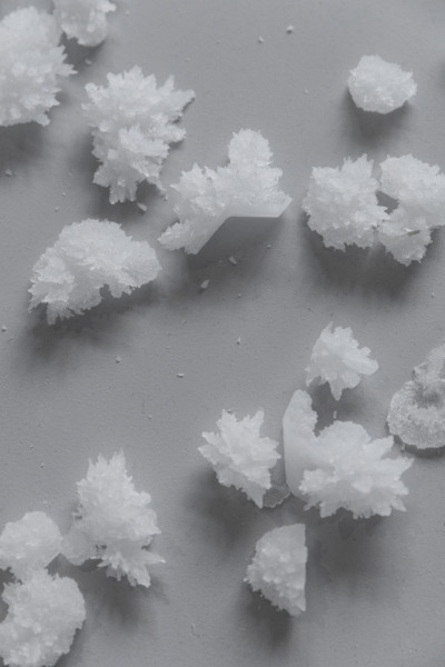 Small heaps of white powder resembling frosted snow on a synthetic grey background