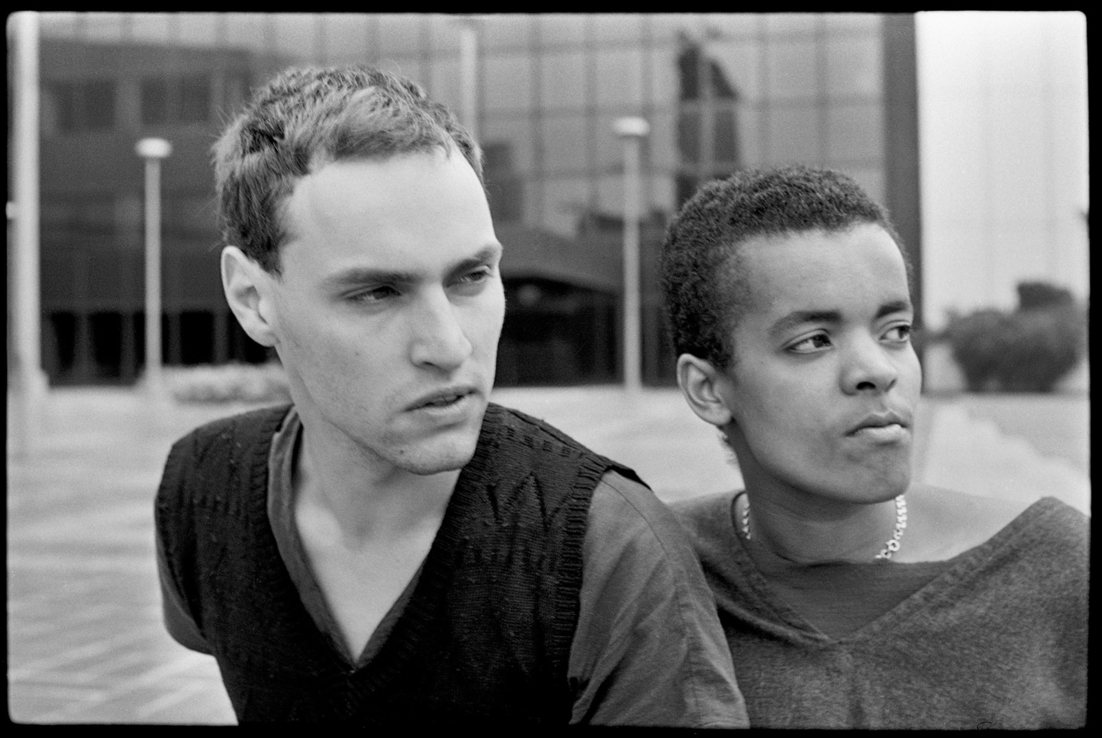 Schwarz-weiße Fotografie von zwei jungen Männern vor einem urbanem Hintergrund