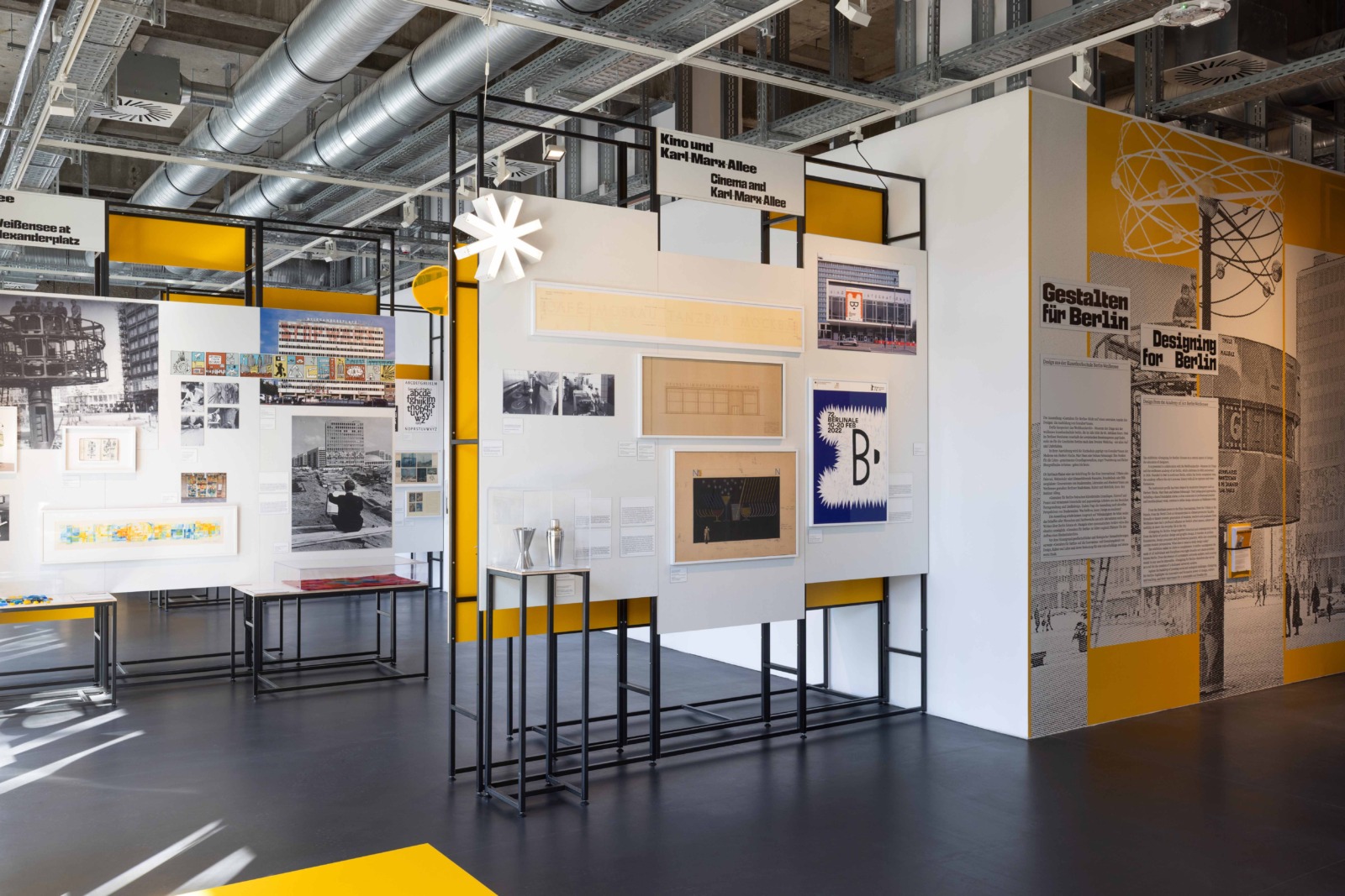 Exhibition view featuring photographs, graphic works, posters, and text panels in a modern museum space