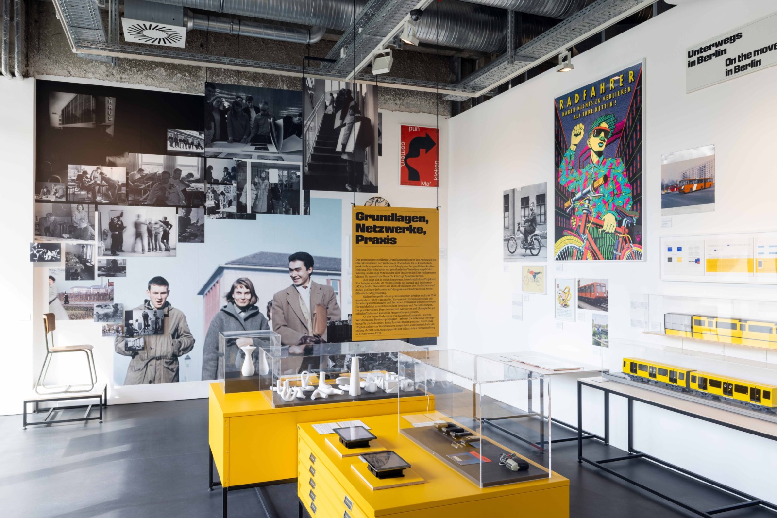 Exhibition view featuring photographs, graphic works, posters, and text panels in a modern museum space