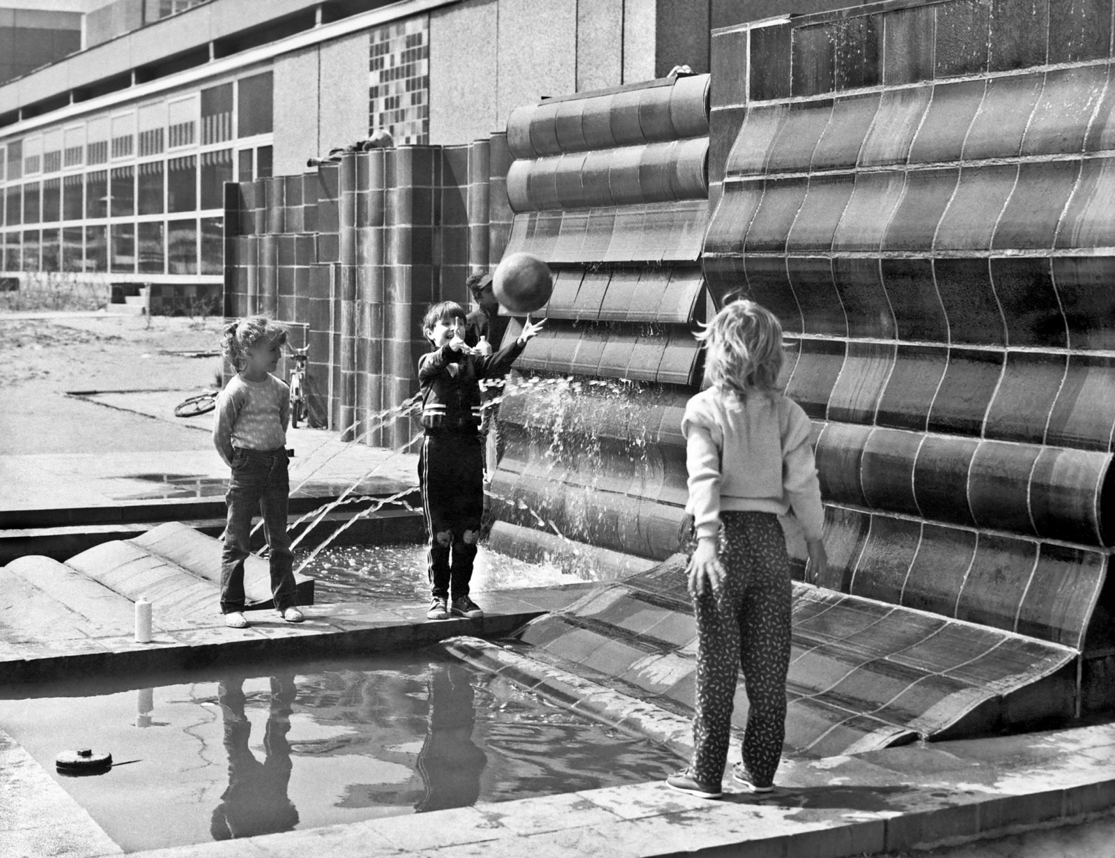 Black-and-white photo of children playing by a fountain