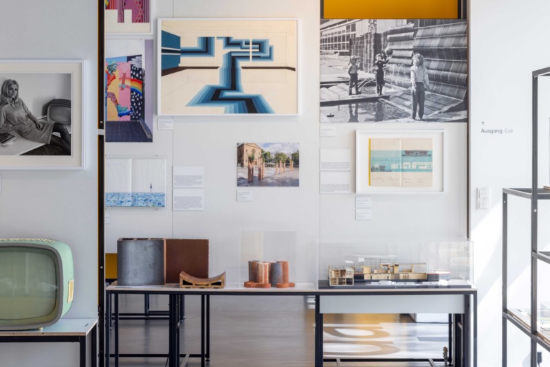 Exhibition view featuring photographs, graphic works, posters, and text panels in a modern museum space
